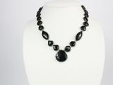 Le collier est composé de perles de verre noires et d'un pendentif en pierre noire.