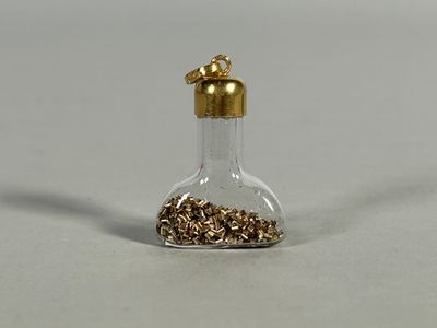 a small glass bottle filled with gold colored beads