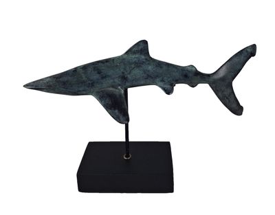 La statue d'un requin est posée sur un socle noir