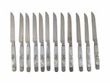 six knives are lined up in a row on a white surface