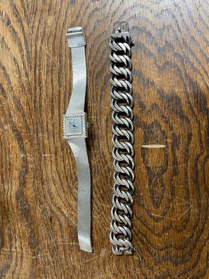 a silver bracelet and a silver watch on a wooden table