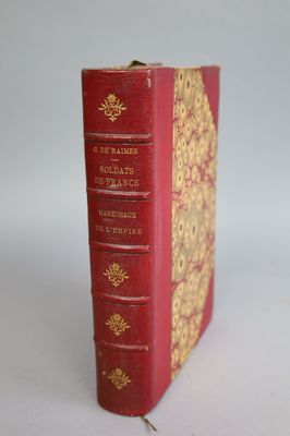 an old red book with gold trim sitting on top of a white surface