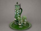 a green plate with a green tea pot and cups on it