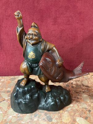 a figurine of a man holding a fish on a rock