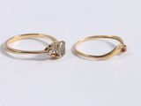 two gold rings with a diamond and a stone on top