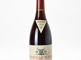 une bouteille de vin de Château Rayne posée sur une surface blanche