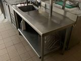 de nombreuses tables en acier inoxydable dans une cuisine équipée d'un évier