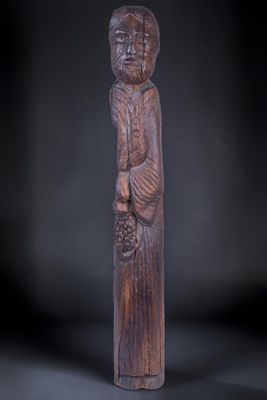 une statue en bois représentant un homme tenant un panier de fruits