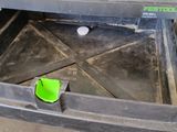 une boîte métallique ouverte, avec un couvercle vert, posée par terre