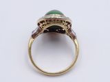 a close up of a ring with a green stone in it