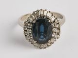 gros plan d'une bague avec une pierre bleue entourée de diamants blancs