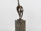 une sculpture en bronze représentant un oiseau posée sur un bloc de marbre