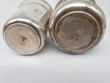two silver salt and pepper shakers on a white surface