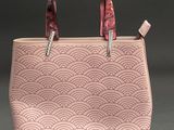 a pink handbag with a pink handle on a grey background