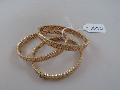 three gold bracelets on a white surface with a price tag