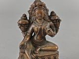 une statue en bronze représentant une femme assise sur une table