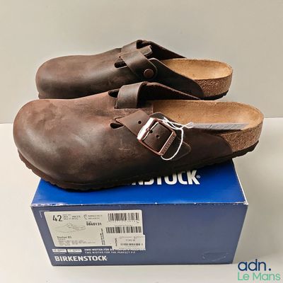 pair of brown clogs sitting on top of a box on a white surface