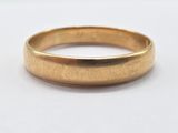 a close up of a gold wedding ring on a white surface