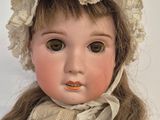 an old fashioned doll with a bonnet and dress on a white background