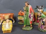 five figurines of a manger, a cow, a manger, and a baby in a manger