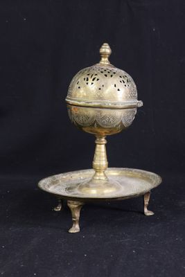 une assiette ancienne en laiton avec un couvercle et un support sur fond noir