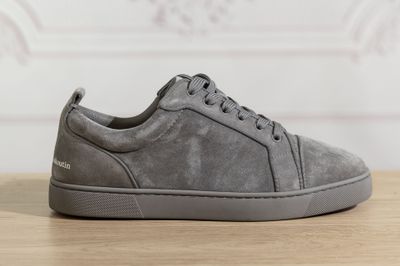 a close up of a pair of grey sneakers on a wooden table