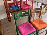 Des chaises aux couleurs vives sont alignées en rang devant une table