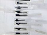 Plusieurs stylos sont alignés en rang sur une surface blanche.