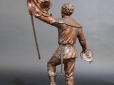 bronze statue of a man holding a flag on top of a wooden base