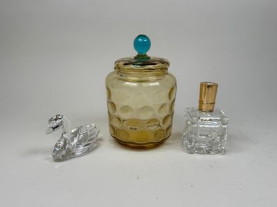 a small glass jar with a blue top next to a small glass bottle with a blue top