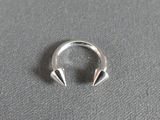 silver plated ring with spikes on it on a gray surface