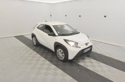 La petite voiture blanche est garée dans le garage, sur le sol à carreaux.
