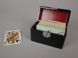 a small black box with cards in it next to a playing card