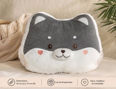un coussin en forme de chat gris et blanc posé sur un canapé, avec une plante en arrière-plan