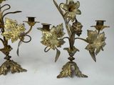 two gold colored candlesticks with flowers on them