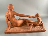 statue of a woman and a child on a sandy surface