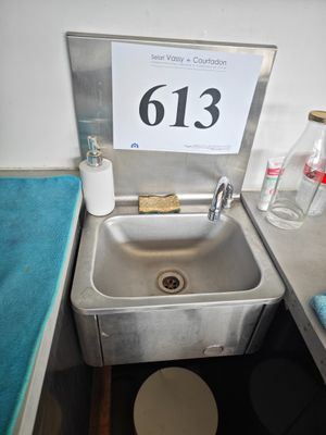 un lavabo dans un coin de la salle de bains, avec une pancarte au-dessus