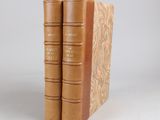 two brown books sitting on top of each other on a white surface