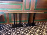 a wooden table with two black legs and a black base