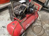 a red air compressor sitting on the floor in the garage