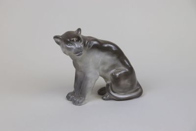statue of a cat sitting on its hind legs on a white surface