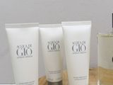 three bottles of body lotion and a glass of water on a wooden tray