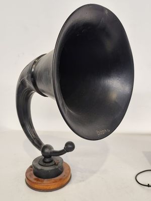 un vieux gramophone noir posé sur un support en bois à côté d'un ordinateur portable