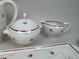 three pieces of pottery on a table with a tray and a pitcher