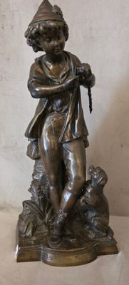 statue en bronze représentant un garçon avec un chien, posée sur un socle en marbre
