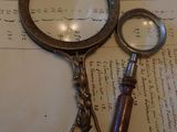 une loupe et une paire de ciseaux posés sur une feuille de papier