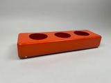 un gros plan d'un pot à crayons orange posé sur une surface blanche