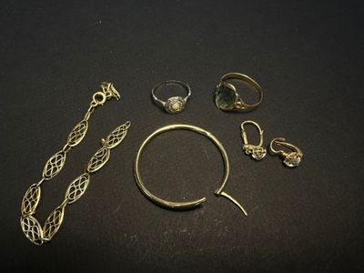 several gold rings and bracelets laid out on a black surface