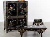 a black cabinet with flowers on it and a small table with a bowl on it