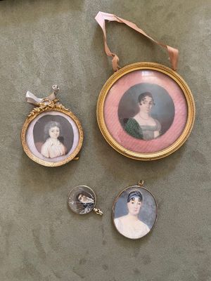 trois portraits miniatures de femmes sont exposés dans un cadre doré posé sur une table